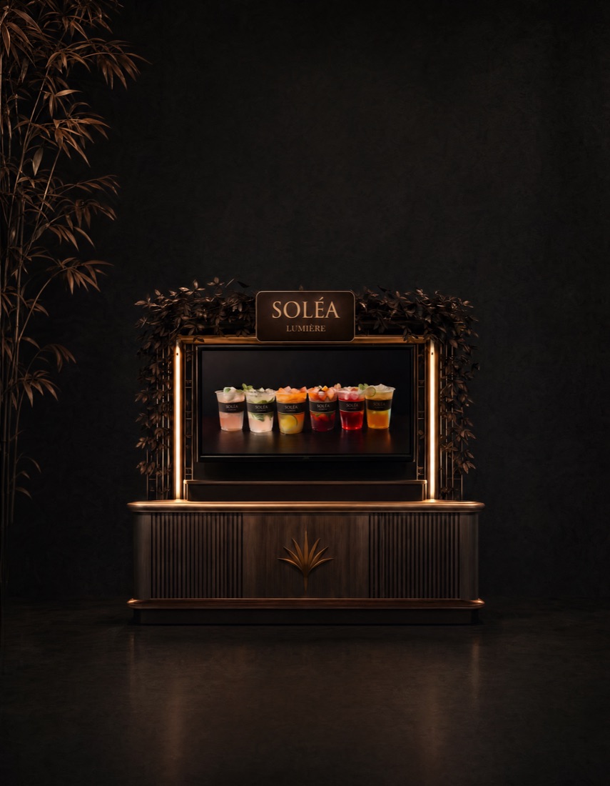 The Soléa Lumière mobile bar, lit in gold, with a screen showing a row of cocktails